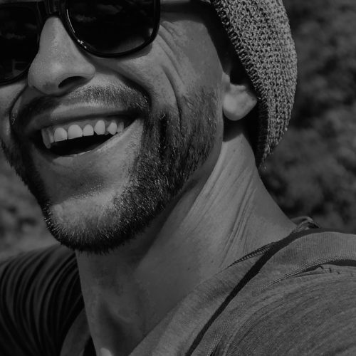 Young male hipster traveler doing selfie overlooking the tropical sea. Adventure, vacation, wonderlust, internet, technology concept.